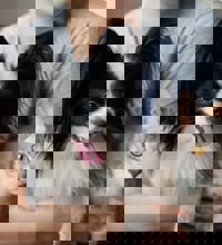 Person der sidder med en hund og en kat i armene.